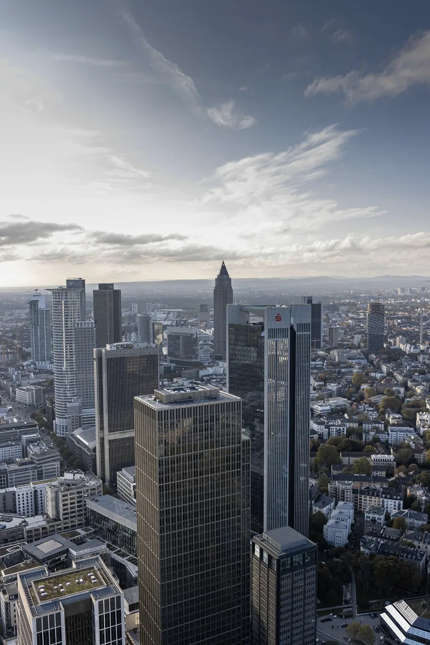 View from a high floor over Frankfurt's banking towers and the city below, clouds in a blue sky.